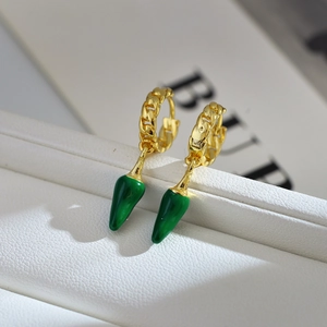 Macro shot of gold-plated chain earrings featuring a vibrant green pepper-shaped pendant