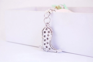Close-up of silver cowboy boot keychain with rhinestone stars and metallic finish