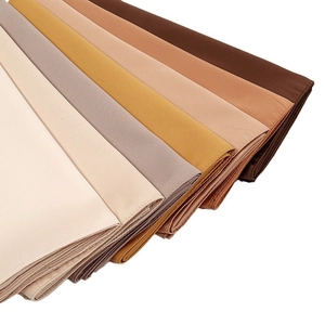 Stack of elegant breathable matte satin silk square scarves in neutral brown and beige tones