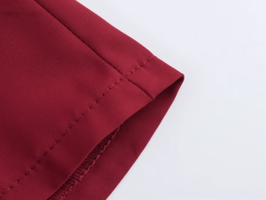 Detail eines roten Tweed-Kleid-Ärmels mit hochwertigen Nähten und strukturierter Strickware