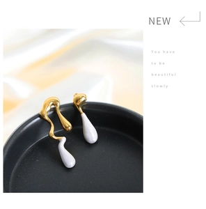 Detail of asymmetrical gold teardrop earrings with purple enamel on black display