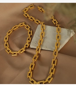 Detailed view of polished 18k gold Cuban chain necklace and bracelet on stone base