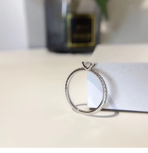 Macro view of silver square diamond ring with side accent stones on a white cube