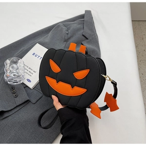 Detail of black leather pumpkin bag featuring orange face and cute bat charm accessory