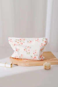 Close-up of white floral cotton makeup bag on wooden board with soft lighting