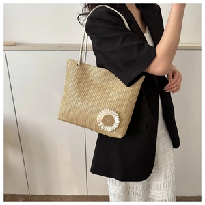 Detail of beige woven tote bag with 3D floral accent and thick rope straps