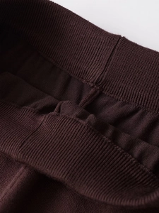 Detail view of the high-density knit ribbing and elastic waist on deep brown knit pants