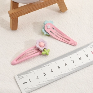 Set of 2 colorful floral hair clips for girls with measurement ruler on white fabric