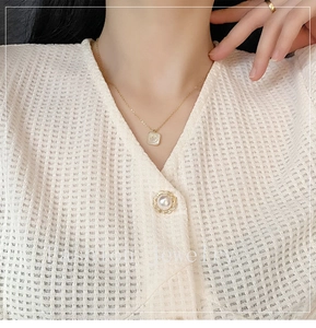 Close-up of golden titanium necklace with square shell smiley face pendant on model