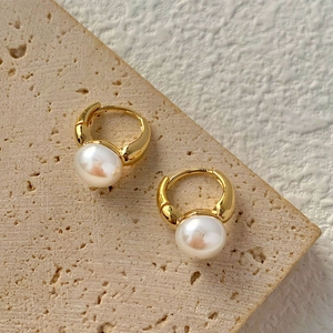 Vista macro dettagliata di orecchini a cerchio dorati con eleganti perle barocche bianche