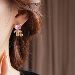 Detail of asymmetrical teddy bear earrings with pink crystal and heart pendant on ear
