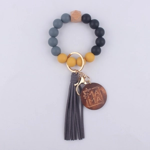 Silicone beaded keychain detail featuring engraved wooden MAMA charm and chic leather tassel.