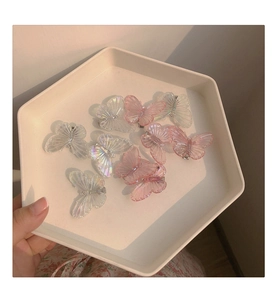Détail de barrettes papillon translucides roses et irisées dans un plateau blanc