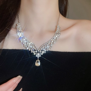 Close-up of sparkling V-shaped crystal necklace with teardrop pendant on female neck
