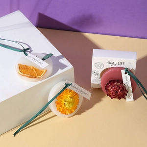 Artistic close-up of handmade floral wax tablets with dried orange and ribbons