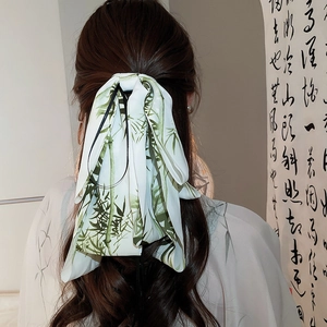 Detail of silk hair ribbon with bamboo print tied in a bow on a wavy half-up hairstyle