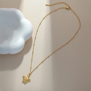 Macro shot of gold-plated starfish pendant necklace with detailed shell texture on beige base