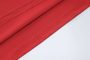 Macro del tessuto del vestito estivo rosso con cuciture professionali a doppio ago catenella