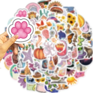 Hand holding a cute cat paw sticker from a 100pcs waterproof cartoon DIY collection