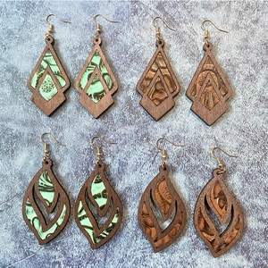 Vintage wood earrings with leather inlay in diamond and teardrop shapes on stone background