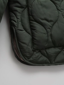 Close-up of diamond quilted pattern and stitching details on dark green jacket