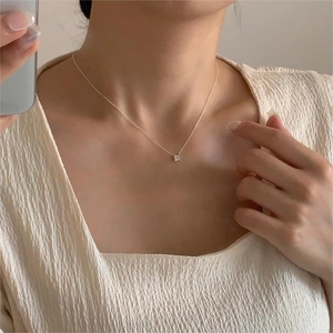 Minimalist gold necklace with a square zircon pendant shown as worn on the neck