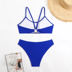 Flat lay of royal blue bikini with gold ring details and summer vacation props