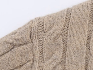 Close-up of cable knit texture on camel wool sweater shoulder with soft fibers