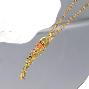 Detailed view of flexible gold-plated fish pendant with colorful crystals on stones