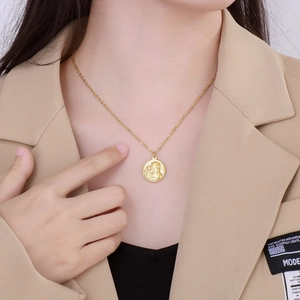Macro detail of a gold round pendant necklace featuring an embossed mother and child design