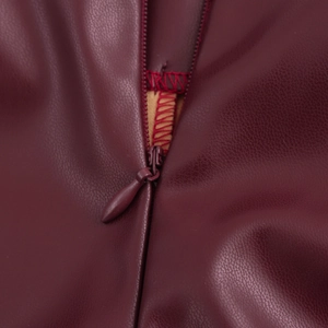 Close-up of invisible zipper detail on dark red faux leather sleeveless crop top and shorts
