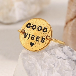 Detail of 18K gold plated ring with Good Vibes engraving on a textured round disc