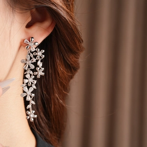 Detailed close-up of sparkling silver flower tassel earrings with zircons on model
