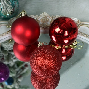 Three red Christmas ball ornaments in matte, glossy, and glitter finishes on mirror
