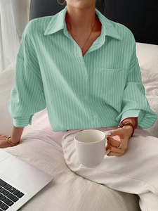 Close-up of light green striped button-down long sleeve shirt in a cozy casual setting