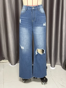 Close-up of high-waist blue washed wide-leg jeans with distressed ripped knee detail