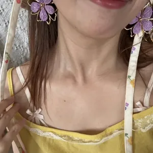 Handmade purple woven flower stud earrings with gold trim worn by a model in a summer style