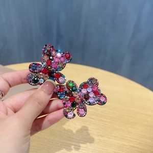 Close-up of bear-shaped hair clips with colorful rhinestones held in hand