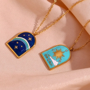 Close-up of 18K gold plated necklaces with blue enamel sun and star tarot pendants