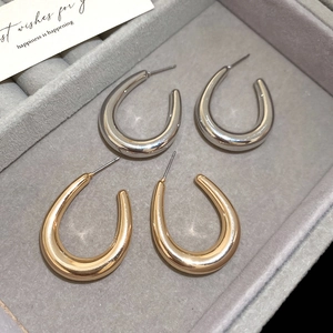 Polished gold and silver U-shaped hoop earrings displayed in a grey velvet jewelry box