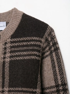 Close-up of brown and black plaid knit cardigan with crew neck and thick fabric texture