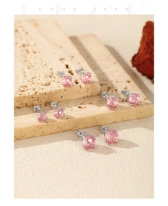 Detail view of pink gemstone stud earrings with silver 4-prong setting on stone background