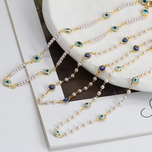 Detail of evil eye pearl necklaces with gold plating and blue enamel charms