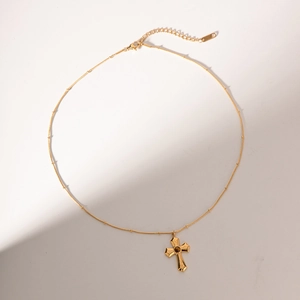 Detailed close-up of golden cross necklace with vintage textured hammer pattern and tiger eye