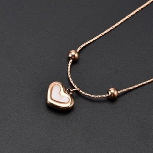 Minimalist rose gold heart necklace featuring a white shell inlay on a dark textured base