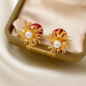 Macro detail of gold earrings with pearls and red beads on luxury velvet display