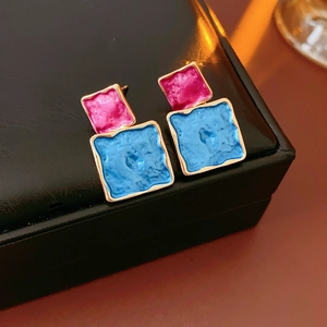 Macro view of colorful drip oil square studs with blue and pink enamel texture