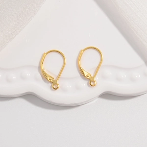 Minimalist pair of golden leverback earring hooks on a wavy white ceramic tray for DIY jewelry