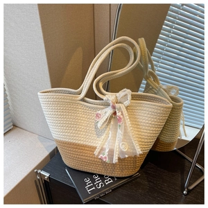 Detail of hand-woven tote bag with bicolor texture and a floral lace ribbon accessory