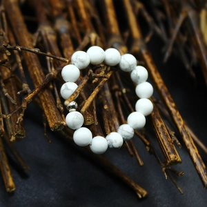 Close-up of 4mm white turquoise stone beads on an elastic ring over dried bamboo sticks